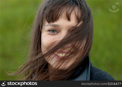 Outdoor portrait of beautiful happy girl laughing while the wind moves her hair
