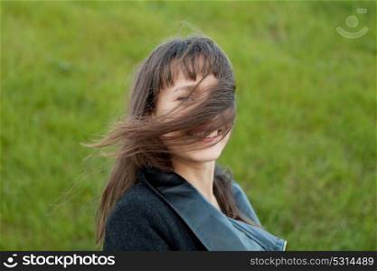 Outdoor portrait of beautiful happy girl laughing while the wind moves her hair