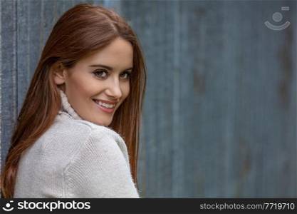 Outdoor portrait of beautiful happy girl or young woman with red hair wearing a white jumper smiling with perfect teeth