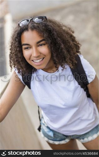 Outdoor portrait of beautiful happy mixed race African American girl teenager female young woman smiling with perfect teeth wearing shorts, t-shirt and back pack