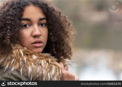 Outdoor portrait of beautiful happy mixed race African American girl teenager female child in fake fur lined coat