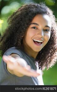 Outdoor portrait of beautiful happy mixed race African American girl teenager female young woman smiling with perfect teeth holding hand to camera