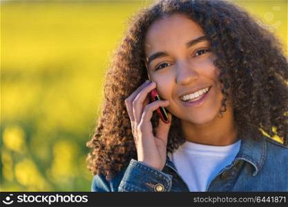 Outdoor portrait of beautiful happy mixed race African American girl teenager female young woman Talking on cell phone and smiling with perfect teeth