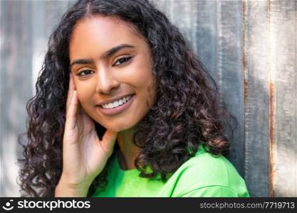 Outdoor portrait of beautiful happy mixed race African American girl teenager female young woman thinking and smiling with perfect teeth in an urban city background