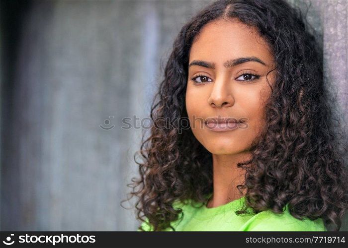 Outdoor portrait of beautiful happy mixed race African American girl teenager female young woman thinking and smiling with an urban city background