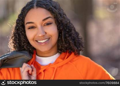 Outdoor portrait of beautiful happy mixed race biracial African American girl teenager female young woman laughing and smiling with perfect teeth in golden evening sunshine
