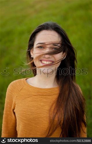 Outdoor portrait of beautiful happy teenager girl laughing while the wind moves her hair