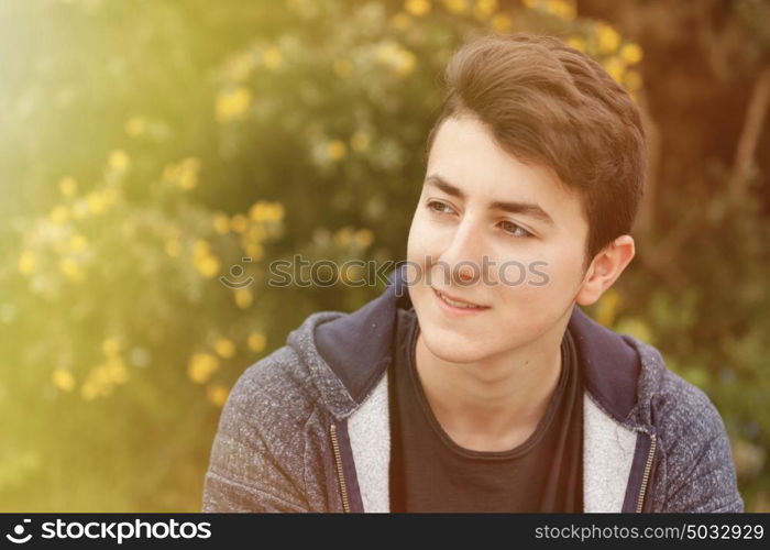 Outdoor portrait of beautiful happy teenager guy relaxed under a sunny day