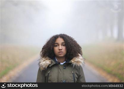 Outdoor portrait of beautiful mixed race African American girl teenager female child outside in a park on foggy day