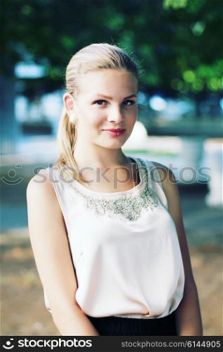 outdoor portrait of beautiful stylish young woman wearing black skirt and beige silk blouse