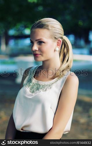 outdoor portrait of beautiful stylish young woman wearing black skirt and beige silk blouse