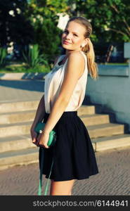 outdoor portrait of beautiful stylish young woman wearing black skirt and beige silk blouse