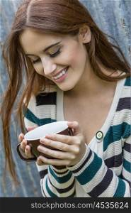 Outdoor portrait of happy beautiful girl or young woman with red hair laughing and drinking coffee