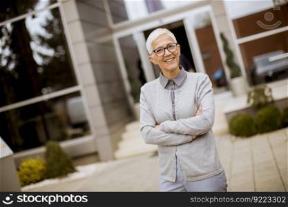 Outdoor portrait of happy cheerful senior businesswoman with crossed arms