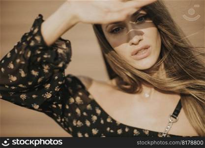 Outdoor portrait of sensual long hair brunette woman covering her face with hand from sunlight