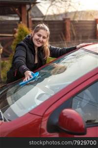 Outdoor portrait of woman washing car windscreen
