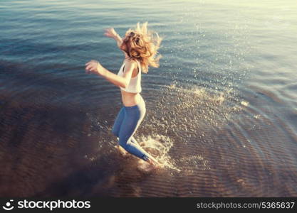 outdoor portrait of young beautiful blonde woman jumping in waves