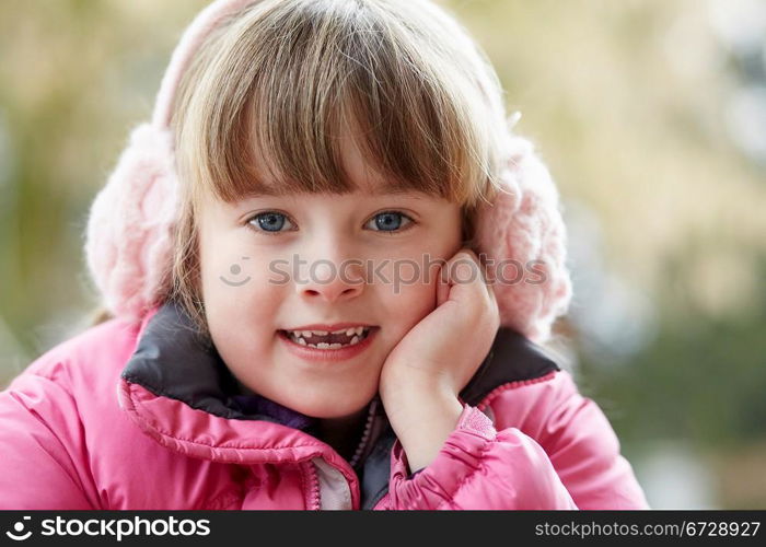 Outdoor Portrait Of Young Girl Wearing Winter Clothes And Earmuffs