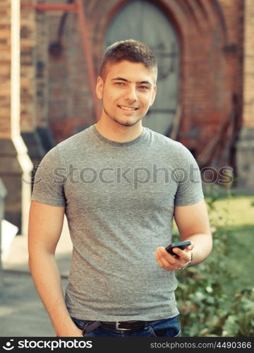 Outdoor portrait of young man in urban context with mobile phone