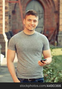 Outdoor portrait of young man in urban context with mobile phone