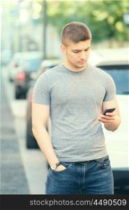 Outdoor portrait of young man in urban context with mobile phone