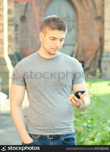 Outdoor portrait of young man in urban context with mobile phone