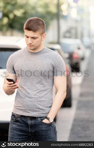 Outdoor portrait of young man in urban context with mobile phone