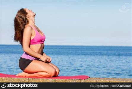 Outdoor relax, sport, fintess concept. Woman in sports suit sitting on dyke, relaxing before workout, sea in background. Woman in sportswear sitting on dyke by sea