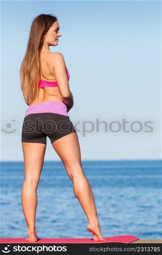Outdoor relax, sport, fintess concept. Woman in sports suit standing on dyke next to sea stretching before workout.. Woman in sportswear standing on dyke by sea