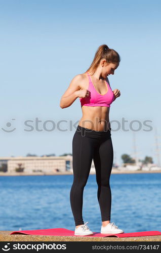 Outdoor relax, sport, fintess concept. Woman in sports suit standing on dyke next to sea stretching before workout.. Woman in sportswear standing on dyke by sea