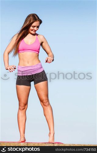 Outdoor relax, sport, fintess concept. Woman in sports suit standing on dyke next to sea stretching before workout.. Woman in sportswear standing on dyke by sea
