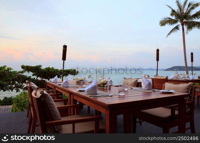 Outdoor restaurant tables, dinner setting at the beach on sunset