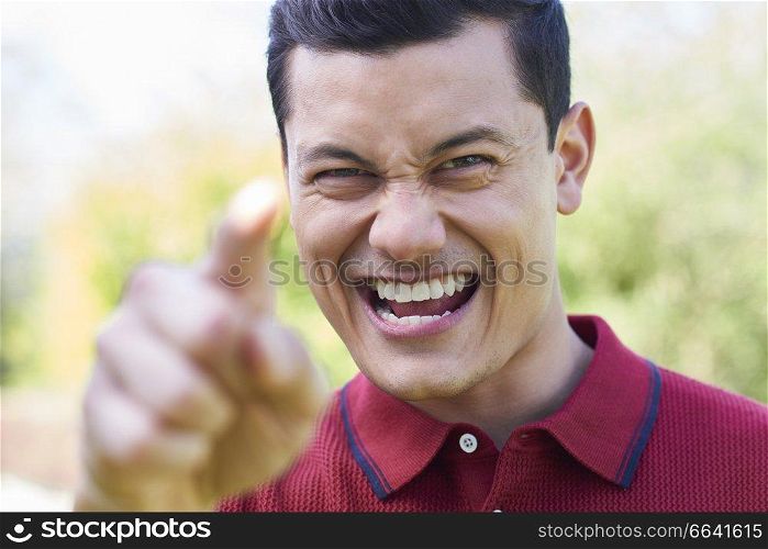 Outdoor Shot Of Angry Young Man Shouting And Pointing At Camera