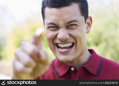 Outdoor Shot Of Angry Young Man Shouting And Pointing At Camera