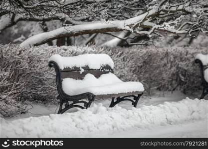 Outdoor shot of bench at park covered in snow