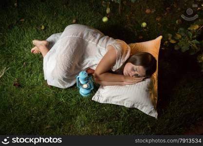 Outdoor shot of cute woman sleeping in garden at night