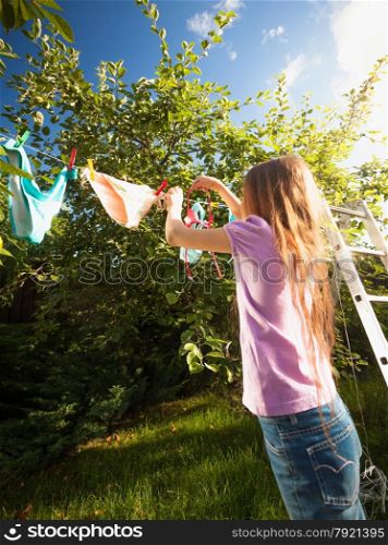 Outdoor shot of girl doing laundry and drying clothes at garden