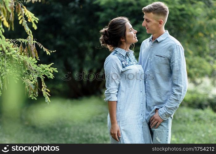 Outdoor shot of young happy couple in love on sunny day on nature. Man and woman hugging, sunlight in summer park. valentine&rsquo;s day. The concept holiday.. Outdoor shot of young happy couple in love on sunny day on nature. Man and woman hugging, sunlight in summer park. valentine&rsquo;s day. The concept holiday