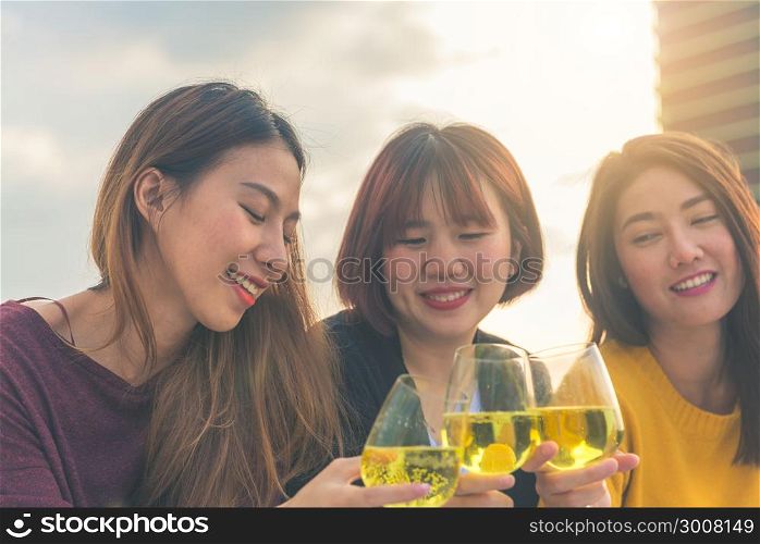 Outdoor shot of young people toasting drinks at a rooftop party. Young asian girl friends hanging out with drinks. Holiday celebration festive party. Teenage lifestyle party. Freedom and fun outdoor.