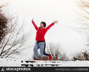 Outdoor sport exercises, sporty outfit ideas. Woman wearing warm sportswear training exercising outside during winter, jumping out of joy.. Woman wearing sportswear exercising outside during winter