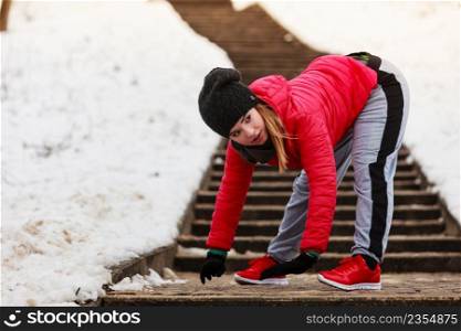 Outdoor sport exercises, sporty outfit ideas. Woman wearing warm sportswear training exercising stretching body outside during winter.. Woman wearing sportswear exercising outside during winter