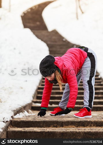 Outdoor sport exercises, sporty outfit ideas. Woman wearing warm sportswear training exercising stretching body outside during winter.. Woman wearing sportswear exercising outside during winter