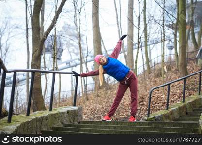 Outdoor sport exercises, sporty outfit ideas. Woman wearing warm sportswear training exercising outside during autumn, warming up before workout.. Woman wearing sportswear exercising outside during autumn