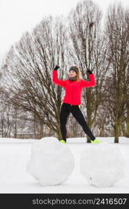 Outdoor sport exercises, sporty outfit ideas. Woman wearing warm sportswear training exercising outside during winter. Having fun while making snowman. Woman wearing sportswear exercising during winter