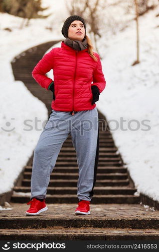 Outdoor sport exercises, sporty outfit ideas. Woman wearing warm sportswear training exercising outside during winter.. Woman wearing sportswear exercising outside during winter