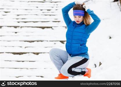 Outdoor sport exercises, sporty outfit ideas. Woman wearing warm sportswear≥tting ready before exercising outside during w∫er.. Woman wearing sportswear exercising outside during w∫er