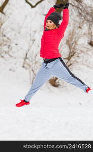 Outdoor sport exercising, sporty outfit ideas. Woman wearing warm sportswear training exercising outside during winter, jumping out of joy.. Woman wearing sportswear exercising outside during winter
