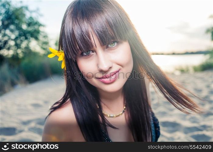 Outdoor summer closeup portrait of young pretty fashion smiling woman with red lips and big eyes with sunflower in her hair