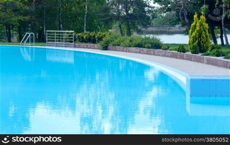 Outdoor swimming pool view with tree reflection on water surface.