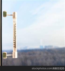 outdoor thermometer with minus 25 degrees celsius temperature on window pane in cold winter day